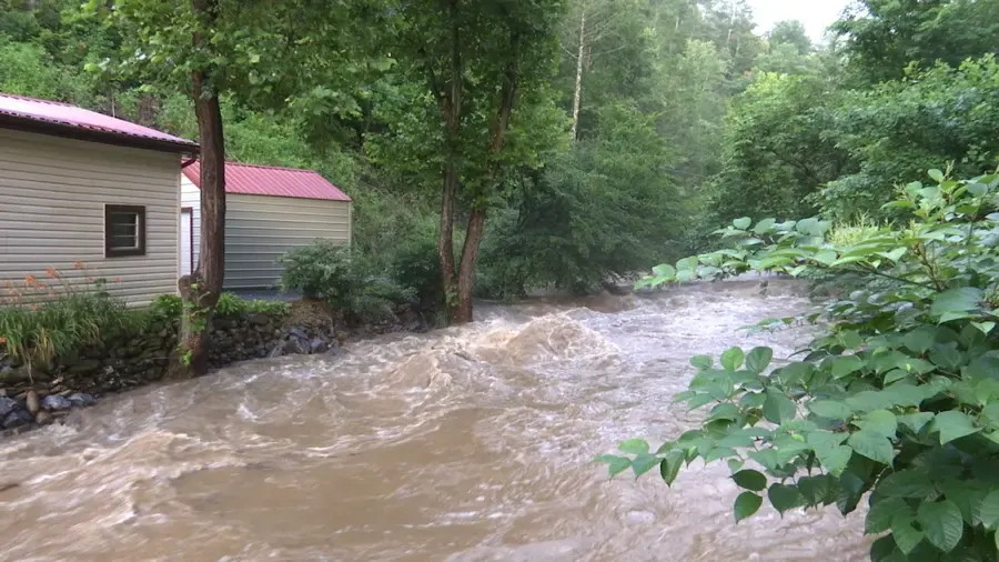 A creek running high and muddy past homes and a shed in Sumner County after heavy rain